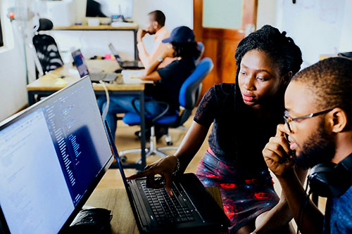 A black women and a black man looking at a computer