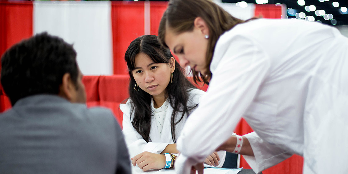 student and preceptor talking with patient at event