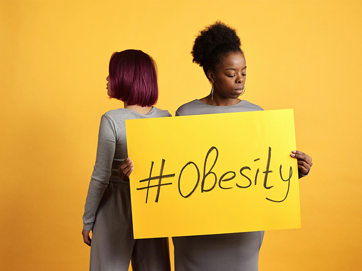 woman holding sign that says obesity